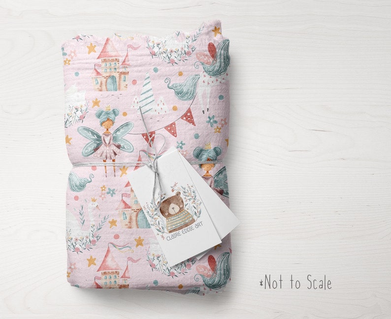 May include: Pink fabric with a repeating pattern of fairies, castles, stars, and flowers. The fabric is folded and tied with a string. A white tag with the text "CLAIRE EDDIE ART" is attached to the fabric.