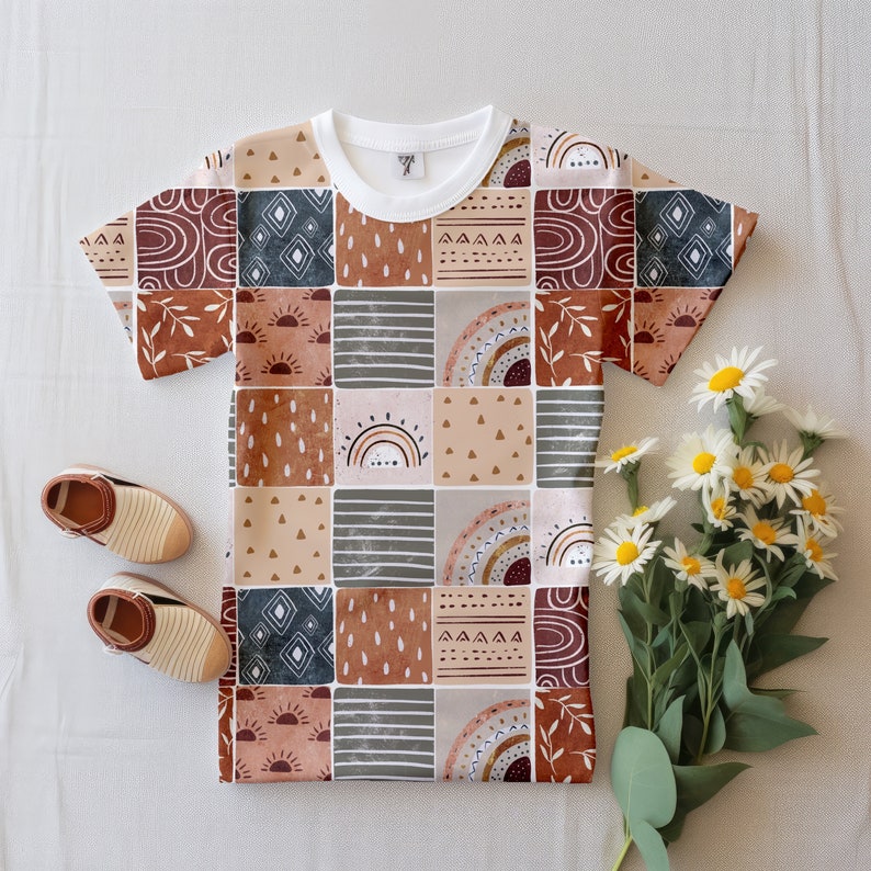 May include: A white t-shirt with a patchwork design featuring geometric shapes, rainbows, and sunbursts in shades of brown, orange, red, and blue.