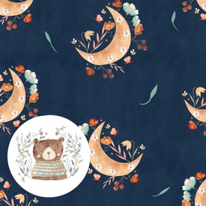 以下が含まれることがあります： ストライプのシャツを着たかわいい茶色のクマが、花と葉の輪で囲まれています。クマは、青い背景の白い円の中心にいます。円は、金色の三日月と花の模様のある濃い青色の背景にあります。