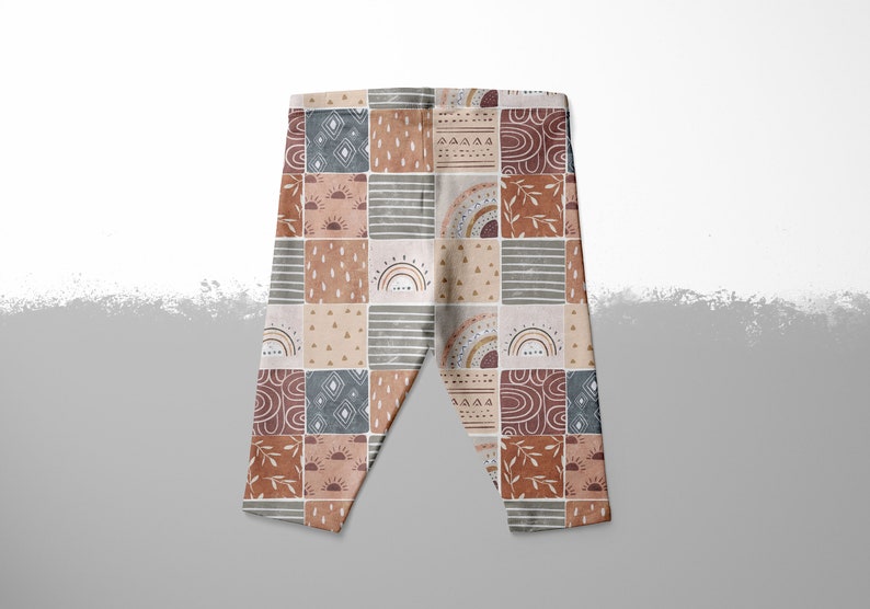 May include: A pair of brown, beige, and blue leggings with a patchwork pattern featuring rainbows, suns, and geometric shapes.