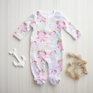 May include: White baby onesie with a pink and purple octopus and jellyfish print. The onesie has a button closure at the neck.