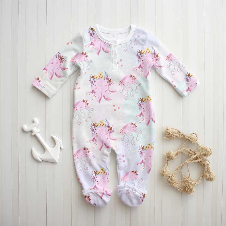 May include: White baby onesie with a pink and purple octopus and jellyfish print. The onesie has a button closure at the neck.