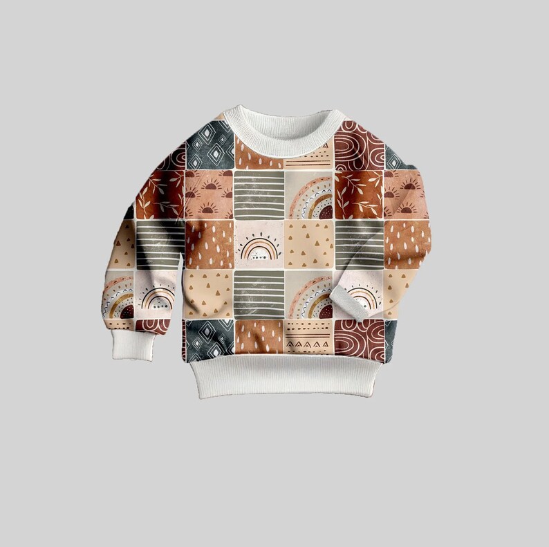May include: A white sweatshirt with a patchwork design featuring geometric shapes, rainbows, and sun motifs in shades of brown, beige, and gray.