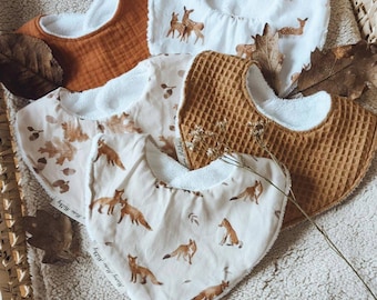 May include: Four different baby bibs with various woodland animal prints. The bibs are made of soft, absorbent fabric and have a white terry cloth backing. The prints include foxes, deer, and leaves.