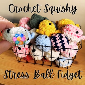May include: A black wire basket filled with various small, round, textured crochet squishy stress ball fidgets in colors including yellow, blue, pink, white, and dark green. One white crochet ball features a multi-colored bubble center.