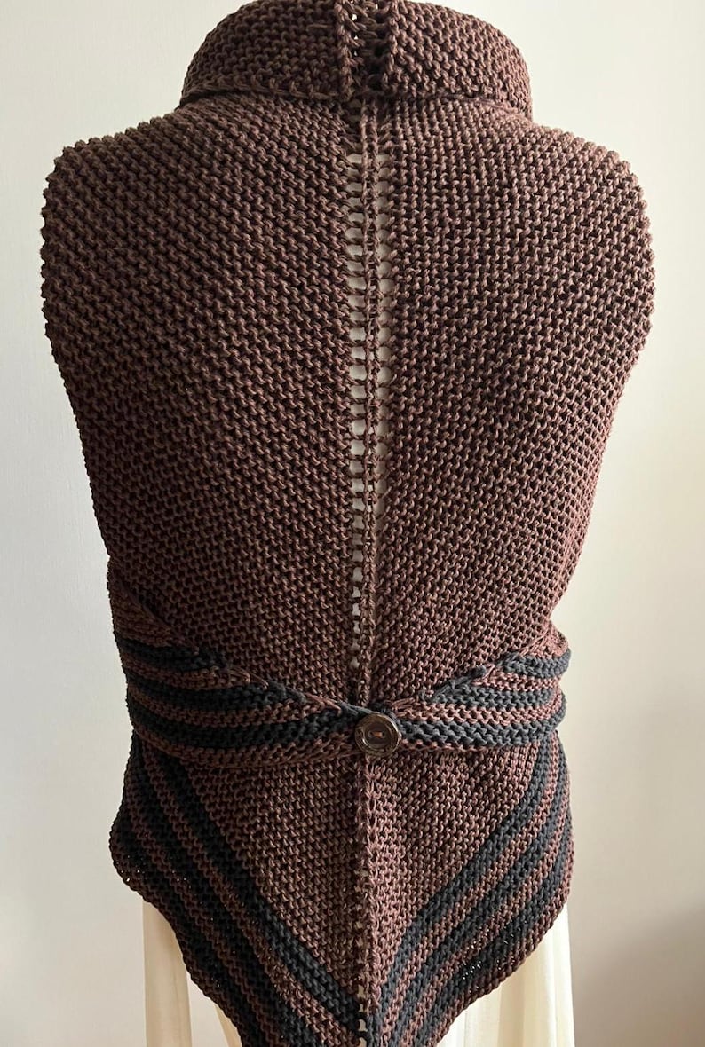 May include: A brown knitted vest with a black trim and a button closure. The vest has a unique open back design.