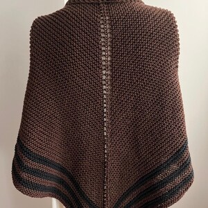 May include: A brown knitted shawl with black stripes along the edges. The shawl is draped over a mannequin.