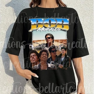 May include: Black t-shirt featuring a graphic of Bob Morales with the text "BOB MORALES" in blue and yellow. The graphic includes multiple images of Bob Morales in various poses. The shirt is a crew neck style.