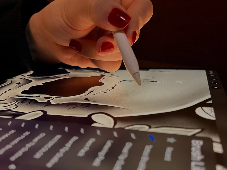 Pu&ograve; includere: Una mano con smalto rosso usa uno stilo bianco per disegnare un teschio bianco e nero su un tablet da disegno digitale.