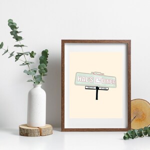 May include: A framed print of a vintage diner sign with the text "Hal's Diner" in pink and green on a light beige background.