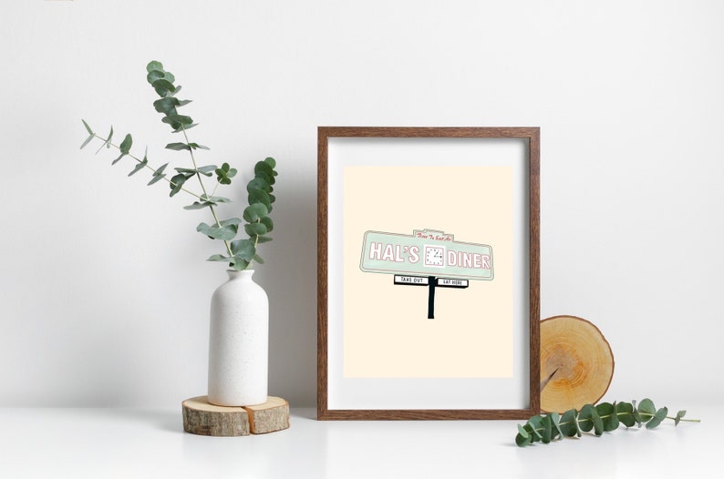 May include: A framed print of a vintage diner sign with the text "Hal's Diner" in pink and green on a light beige background.
