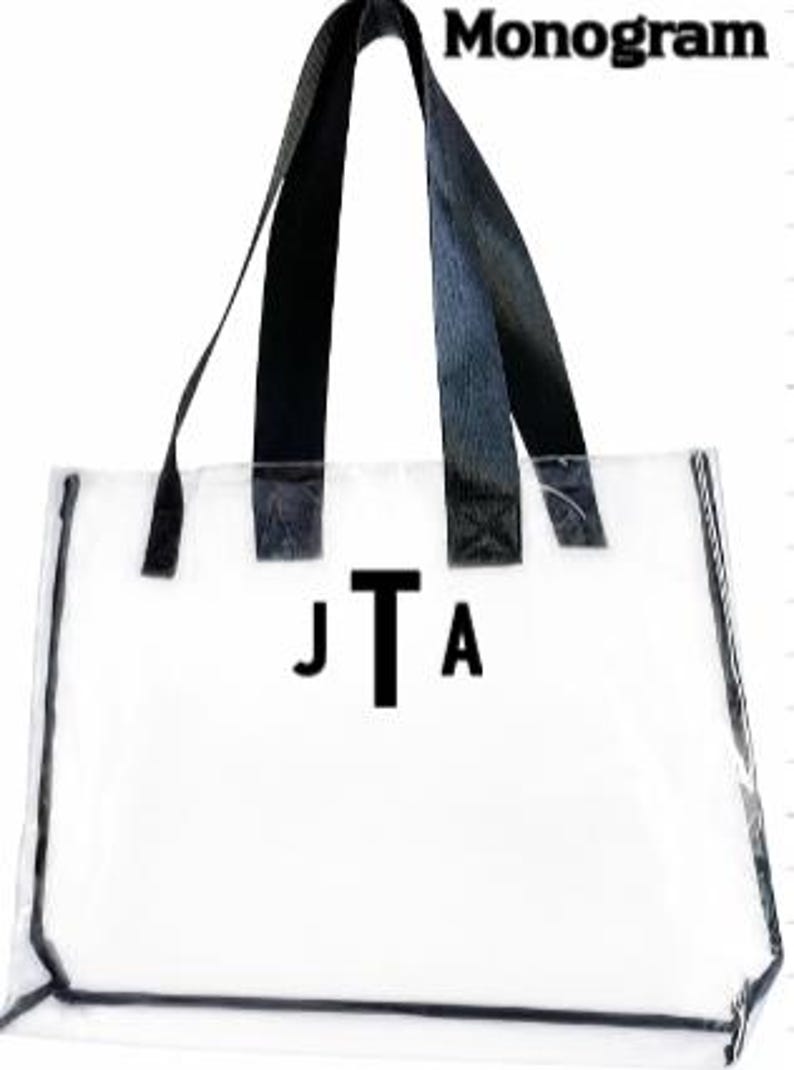 Może przedstawiać: Przezroczysta torba typu tote z czarnymi obramowaniami i uchwytami. Torba posiada monogram "JTA" w czarnych literach. Słowo "Monogram" jest wydrukowane na g&oacute;rze na czarno.