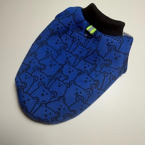 May include: A blue pet vest featuring a repeating black bear pattern. The garment includes a black ribbed collar and a small metal D-ring attachment point accented with a bright yellow and silver reflective strip for visibility.