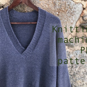Può includere: Un maglione di lana grigio con scollo a V, appeso a un appendiabiti di legno. Il maglione è realizzato a macchina. Il testo "Knitting machine PDF pattern" è sovrapposto all'immagine.