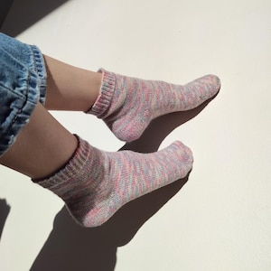 Può includere: Un paio di calzini alla caviglia rosa, blu e bianchi con un motivo marmoreo.