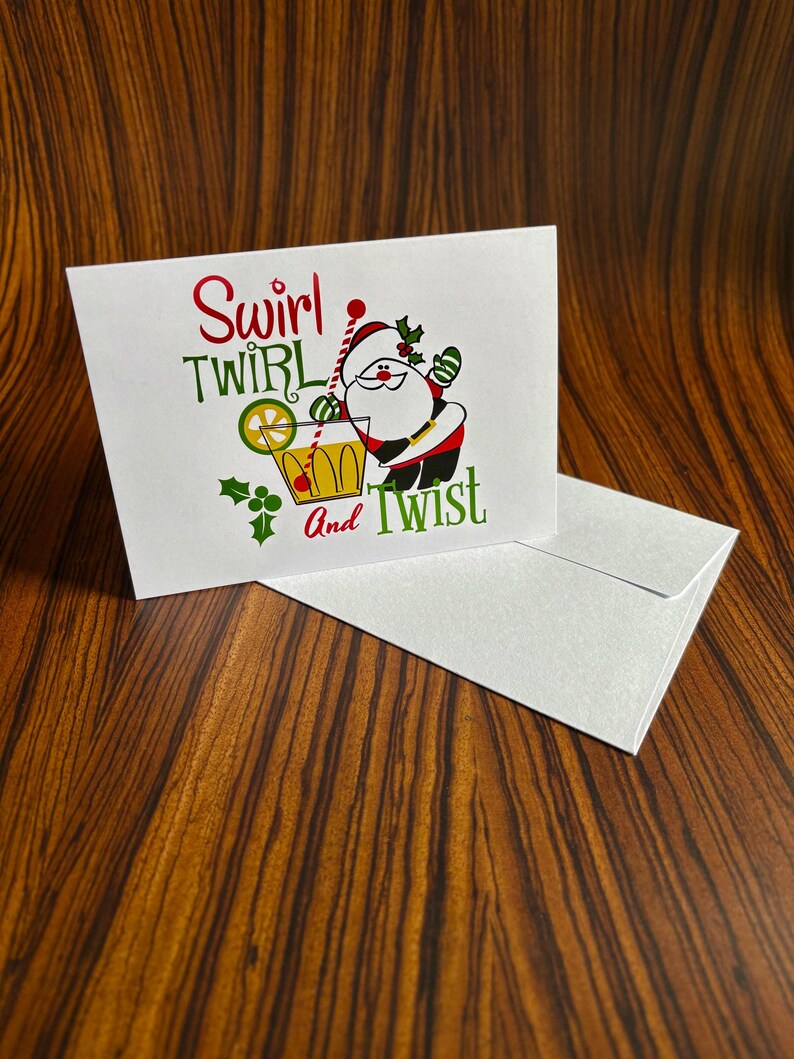 May include: A white Christmas card with a cartoon Santa Claus holding a glass of orange juice with a lime wedge. The text on the card reads "Swirl Twirl And Twist".