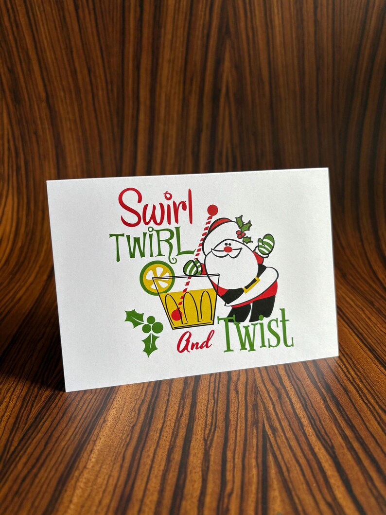 May include: A white card with a cartoon Santa Claus holding a glass of yellow liquid with a lime wedge and a red cherry. The text on the card reads "Swirl Twirl And Twist".