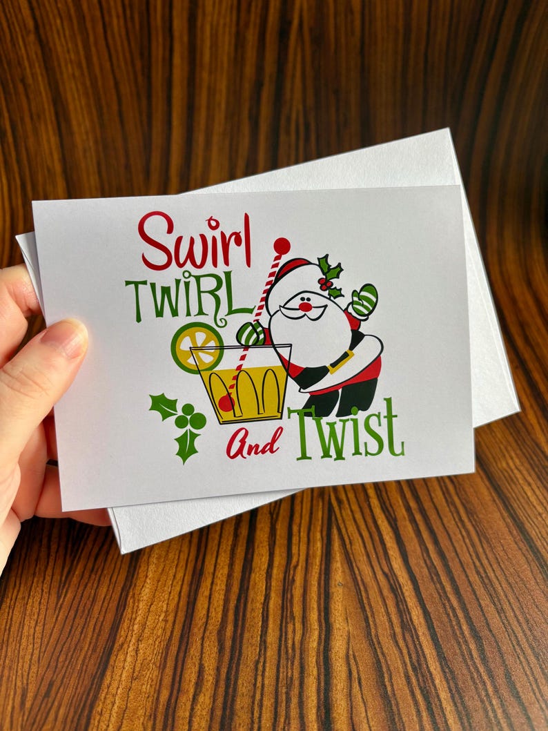 May include: A white Christmas card with a cartoon Santa Claus holding a cocktail glass. The text on the card reads "Swirl Twirl and Twist".