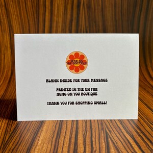 May include: A white card with a red and orange flower logo that says "Hung on You Boutique". The text on the card reads "Blank inside for your message. Printed in the UK for Hung on You Boutique. Thank you for shopping small!"