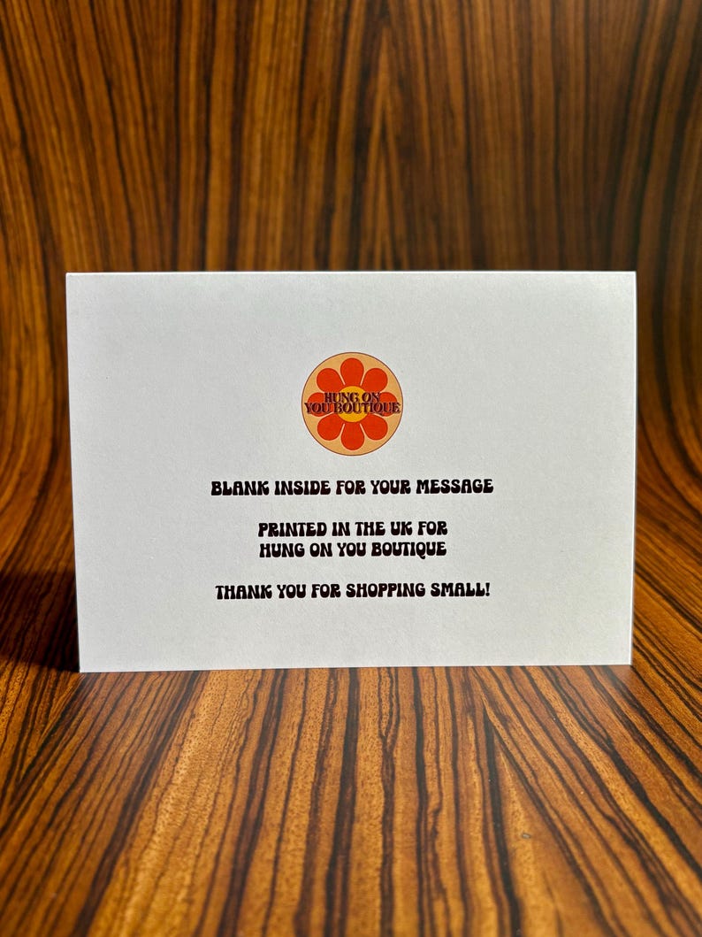May include: A white card with a red and orange flower logo that says "Hung on You Boutique". The text on the card reads "Blank inside for your message. Printed in the UK for Hung on You Boutique. Thank you for shopping small!"