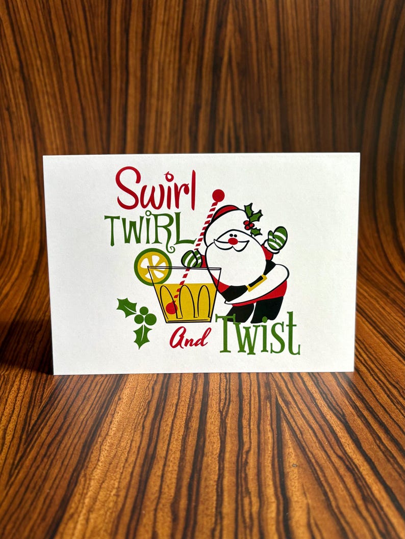 May include: A white card with a cartoon Santa Claus holding a cocktail glass with a lime wedge and a red cherry. The text on the card reads "Swirl Twirl And Twist".