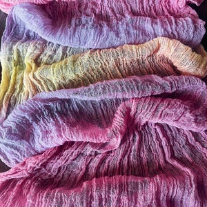 Può includere: Un runner in tessuto leggero e stropicciato caratterizzato da una vivace sfumatura di colori. Il tessuto passa dal rosa intenso nella parte inferiore al viola chiaro, giallo tenue e arancione, terminando con una tonalità rosa brillante in alto.