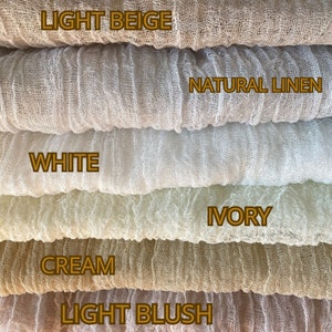 Op de afbeelding: Close-up van stofstalen in verschillende neutrale kleuren. De stalen omvatten lichtbeige, natuurlijk linnen, wit, ivoor, crème en lichtroze. Elke staal heeft een getextureerde, luchtige uitstraling, met de kleurnamen in een vetgedrukte lettertype.