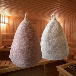 Puede incluir: Dos gorros de sauna c&oacute;nicos hechos de lana de fieltro gruesa. Un gorro es de color marr&oacute;n rojizo apagado y el otro es gris claro. Ambos gorros presentan una parte superior puntiaguda con un peque&ntilde;o lazo integrado para colgar, con una textura densa.