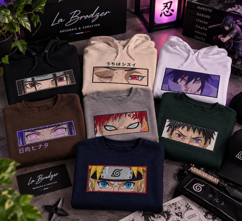 May include: A collection of seven hoodies and sweatshirts in black, beige, white, brown, gray, dark green, and navy blue. Each garment features a rectangular embroidered graphic of anime character eyes with Japanese text above or below the design.