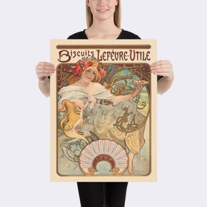 May include: A vintage poster featuring a woman with flowing hair and a floral headdress, holding a plate of biscuits. The poster has a cream-colored background with the text "Biscuits Lefèvre-Utile" and the year "1897" in a decorative font. The artwork is in the Art Nouveau style.