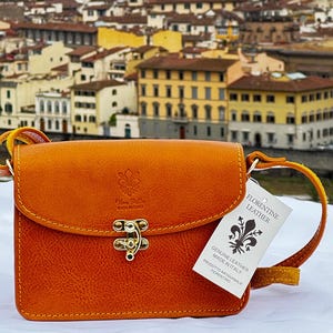 This elegant, handcrafted Italian leather crossbody bag from ChicMilano showcases a rich tan color with fine stitching and brass hardware. Its compact design includes a secure clasp and an adjustable leather strap, perfect for carrying essentials