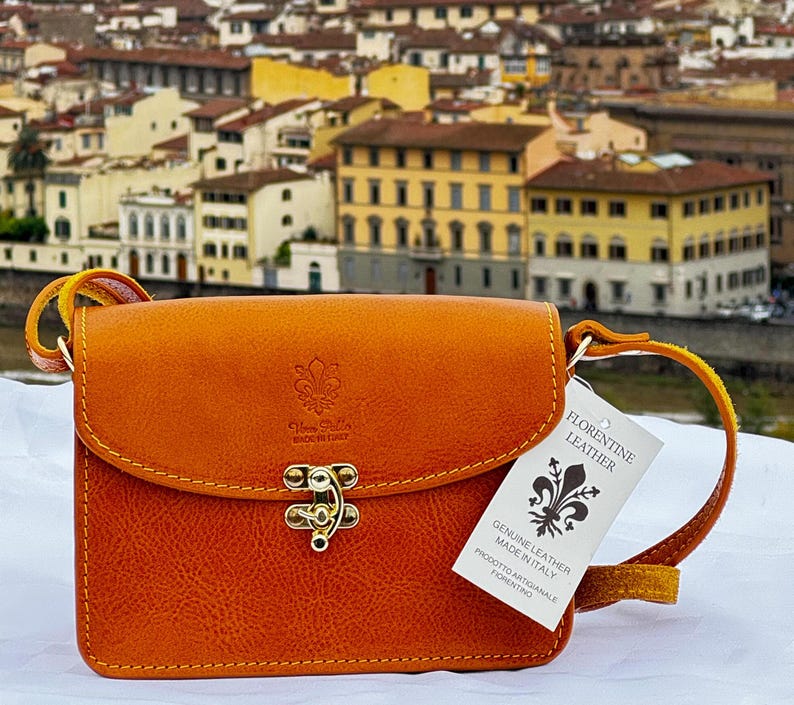 This elegant, handcrafted Italian leather crossbody bag from ChicMilano showcases a rich tan color with fine stitching and brass hardware. Its compact design includes a secure clasp and an adjustable leather strap, perfect for carrying essentials