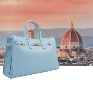 Italian Handmade Leather Bag crafted in Florence from genuine Italian leather, this elegant light blue top handle bag & tote bag blends timeless design with everyday functionality. Featuring structured lines, a refined gold-tone turn-lock closure, and double top handles, it offers a spacious interior with secure zip closure. A versatile leather tote bag made in Italy, perfect for work, city wear, or as a thoughtful gift for her.