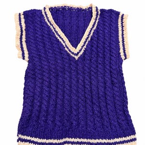 May include: A sleeveless V-neck sweater vest in a deep purple color featuring a vertical cable knit pattern. The neckline, armholes, and bottom hem are finished with cream-colored ribbed trim accented by thin dark purple stripes.