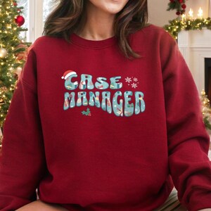 May include: Red Christmas sweatshirt with the text "Case Manager" in a retro font with a Santa hat and snowflakes.