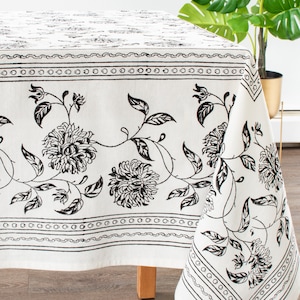 May include: White tablecloth with a black floral pattern. The pattern features stylized flowers and leaves.