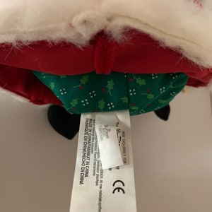 May include: A plush Santa Claus doll with a red coat, white trim, and a green patterned skirt. The tag reads "MADE IN CHINA" and "The (0) Nightmare Christmas". The doll has black boots and a white fluffy beard.