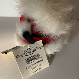 May include: A Disney Store Sound Santa Bean Bag. The plush toy is red with white faux fur trim and black accents. The attached tag reads "SOUND SANTA BEAN BAG".
