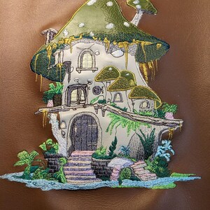 May include: A whimsical mushroom house with a green roof, white spots, and a brown door. The house has two windows and is surrounded by green plants and a blue stream.