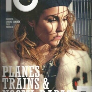 May include: A magazine cover featuring a woman wearing a blue beret and a white fur coat. The cover text reads "Planes Trains & Noomi Rapace".