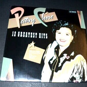 May include: A vinyl record album cover featuring a black and white image of Patsy Cline, a country music singer, with the text "Patsy Cline 12 Greatest Hits" in a colorful font.