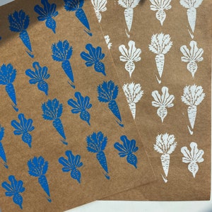 May include: Two sheets of brown paper with a repeating pattern of blue and white carrot prints. The carrots are stylized and have a leafy top.
