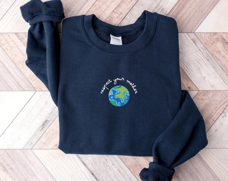 Puede incluir: Una sudadera azul marino con una Tierra bordada en verde y azul y el texto "respeta a tu madre" en la parte delantera.