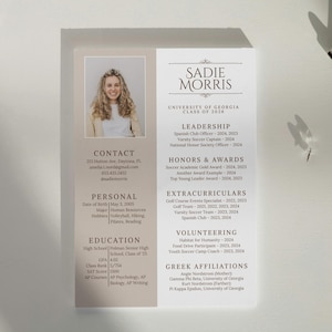 Può includere: Un curriculum vitae con foto, informazioni di contatto e sezioni per leadership, onorificenze, attività extrascolastiche, volontariato e affiliazioni greche. Design minimalista e colori neutri.