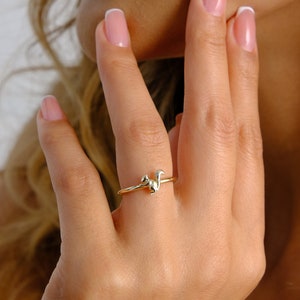 以下が含まれることがあります： リスのデザインの金の指輪。指輪は人の指にはめられています。