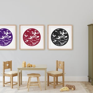 May include: Three framed prints of a stylized black and white design with a circle in the center. The circle contains a Japanese word and a stylized image of a tree and birds. The prints are hanging on a white wall above a wooden table and chairs.