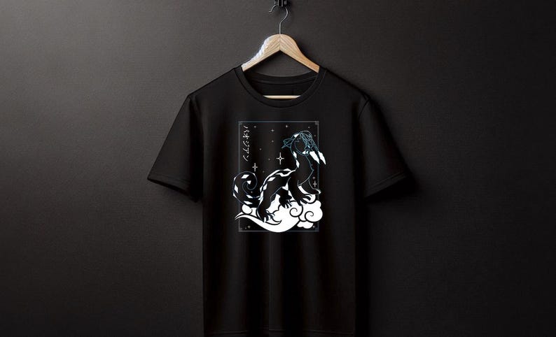 May include: Black t-shirt featuring a white and black illustration of a creature on a cloud, with Japanese text. The design includes stars and a rectangular border. The shirt is hanging on a wooden hanger.