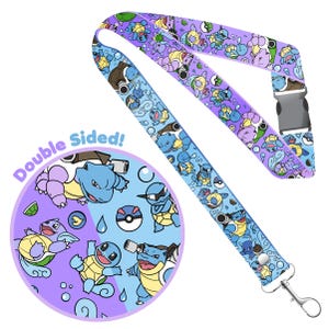May include: Double-sided lanyard with a blue and purple background featuring a repeating pattern of cartoon Squirtle, Wartortle, and Blastoise Pokemon. The lanyard has a metal clip on one end and a plastic buckle on the other end.