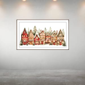 Puede incluir: Pintura a la acuarela de una hilera de casas festivas con fachadas rojas, marrones y beige, adornadas con nieve y árboles de Navidad. La obra de arte está enmarcada y expuesta en una pared blanca, creando una escena navideña acogedora.
