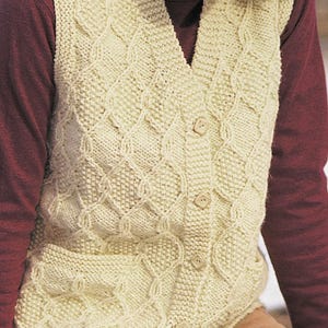 May include: Cream-colored knitted vest with a V-neck and button closure. The vest features a textured diamond pattern and is made of a soft, warm material. A cozy, stylish garment for layering.